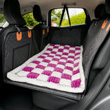 Pink checkerboard Luxe Dog Bed on a car back seat